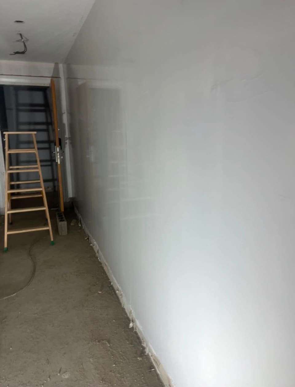 Mur ratissé et mis en peinture blanche dans un appartement en rénovation à Boucau, escabeau de chantier au fond
