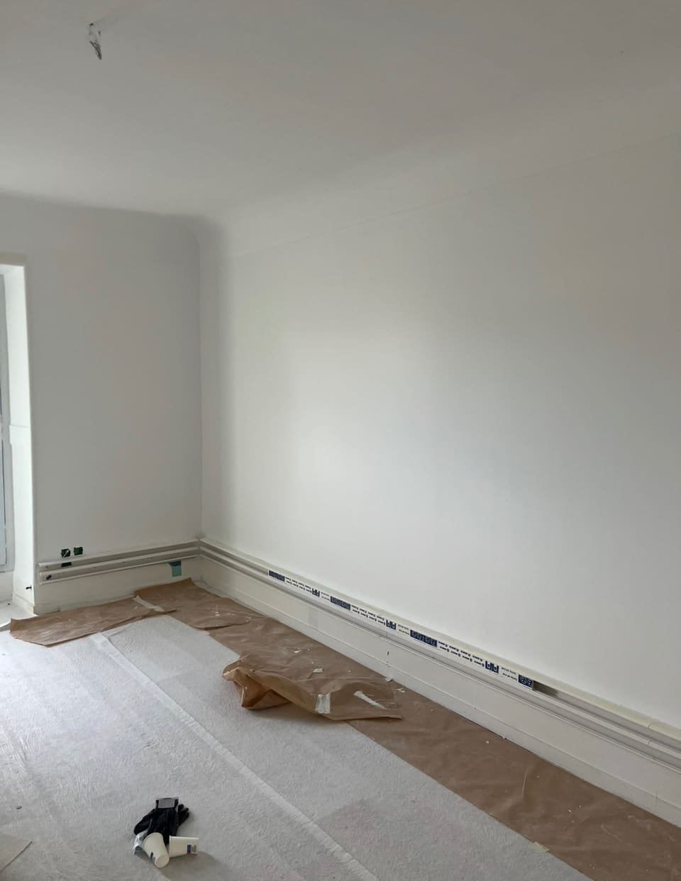 Pièce fraîchement repeinte en blanc dans une maison à Biarritz, sols et plinthes encore protégés