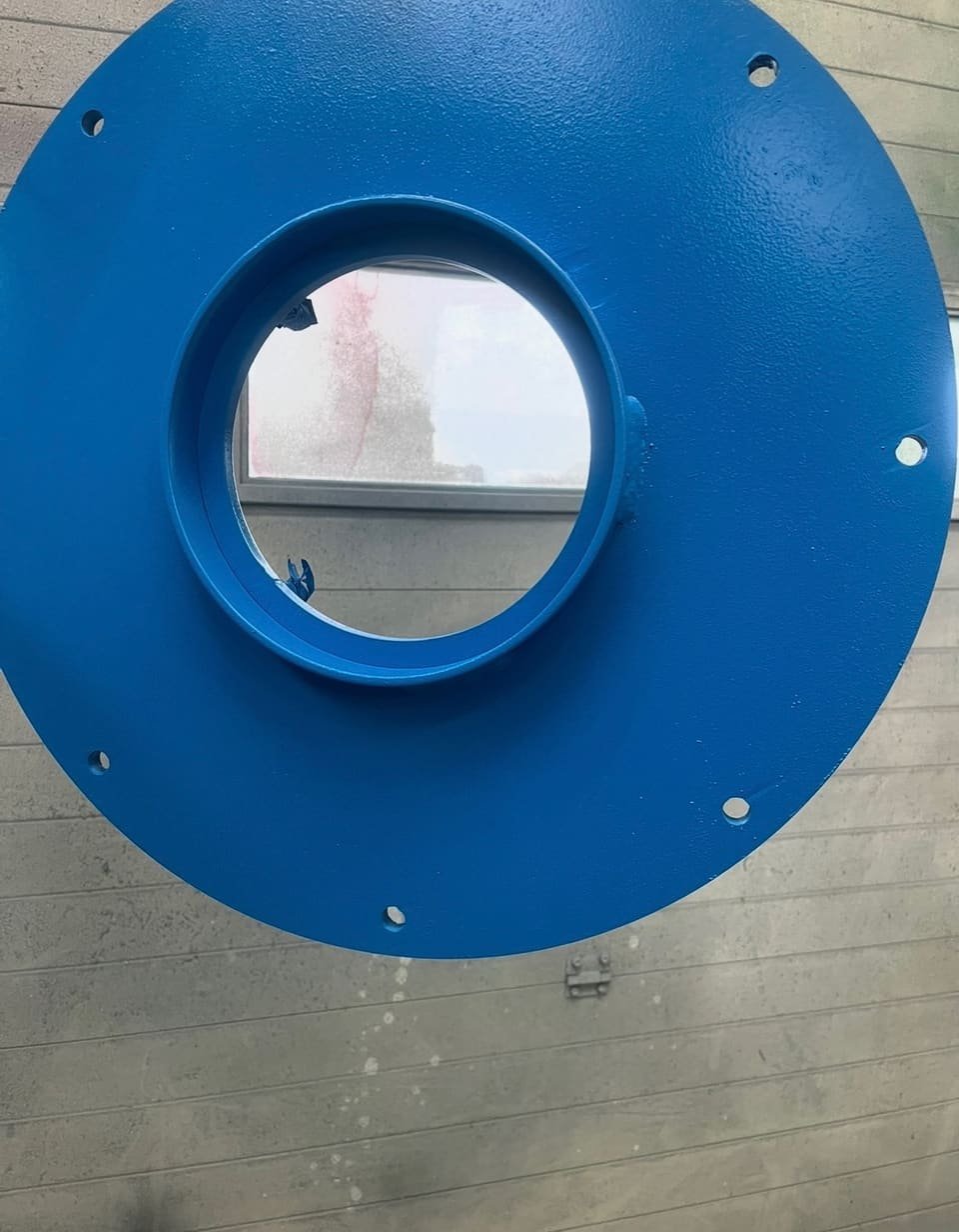 Bride circulaire en acier laquée en bleu, suspendue en atelier après application de la peinture