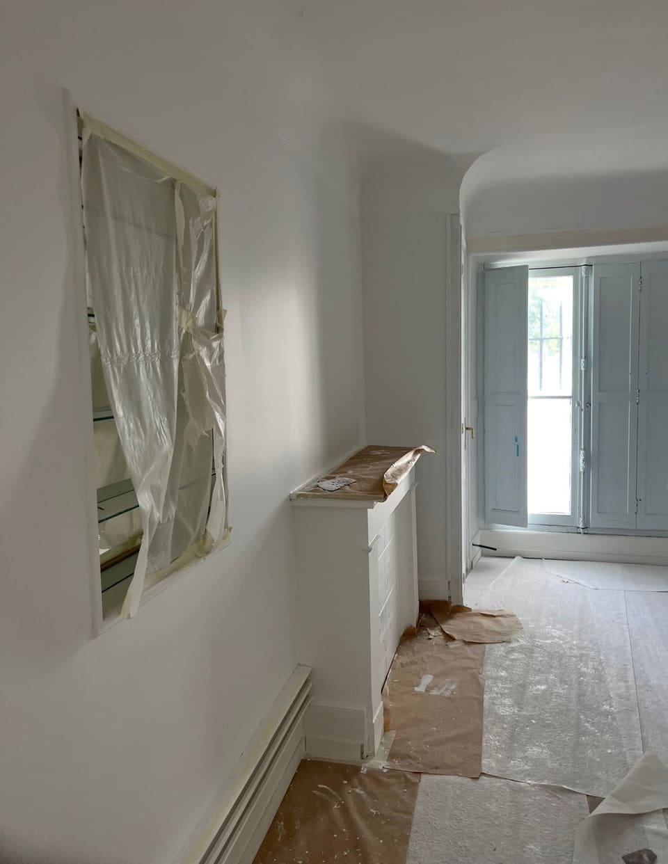 Intérieur en cours de chantier : miroir bâché, sols protégés par cartons et bâches avant mise en peinture
