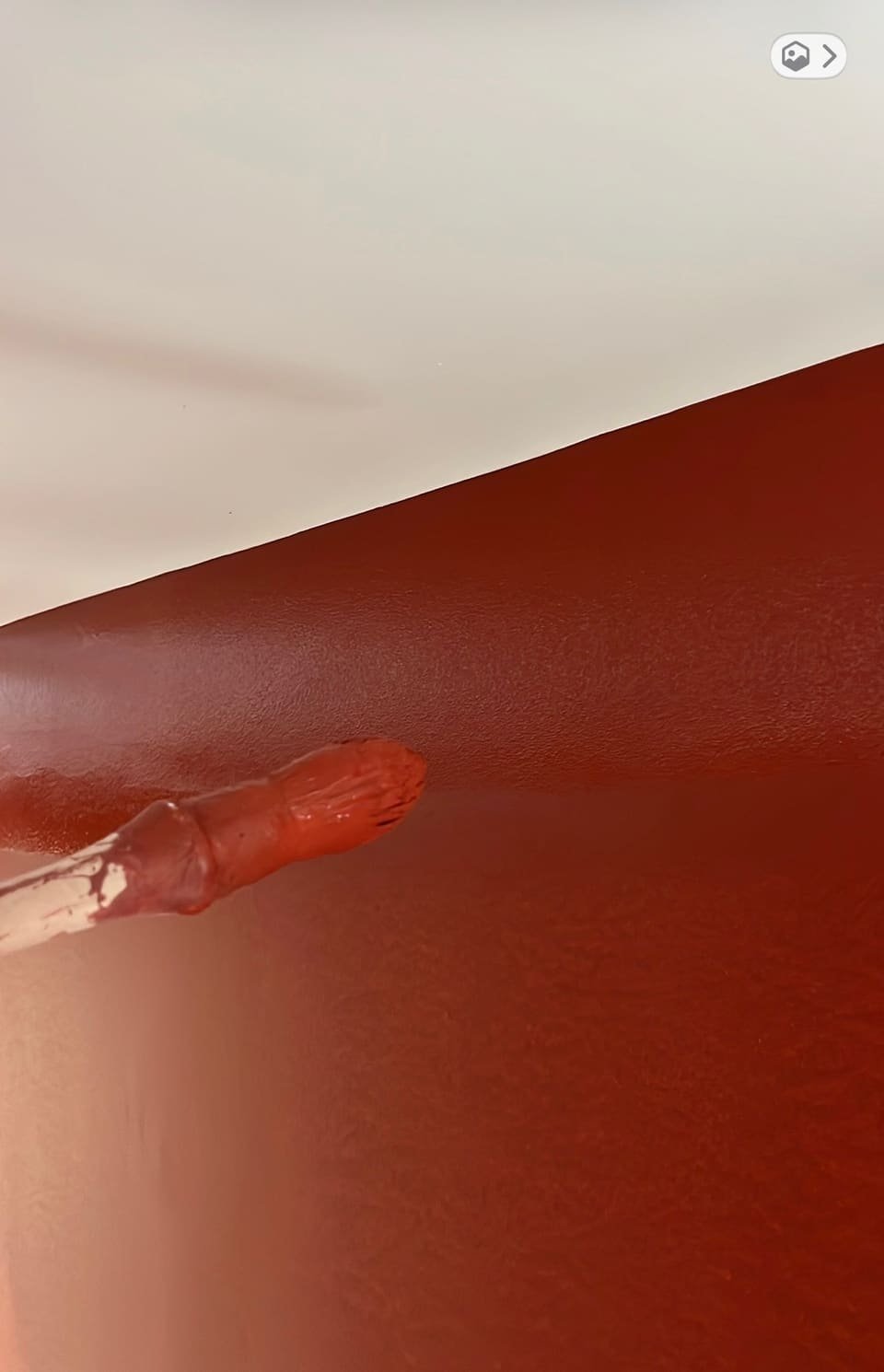 Rechampi au pinceau d’un mur peint en rouge basque sous un plafond blanc, ligne de coupe nette